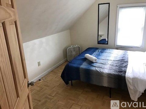 A bedroom with a bed, a mirror, and a window.