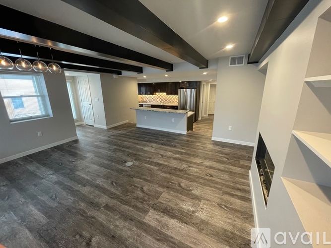 A spacious room with a kitchen area and a staircase.