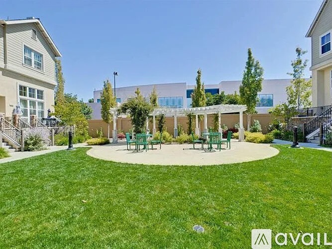 A grassy area with a pavilion and benches in front of a building.