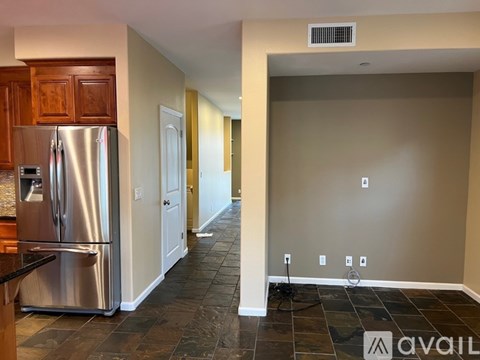 A kitchen with a stainless steel refrigerator and wooden cabinets.