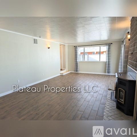 A room with a wood floor and a window with a view of a building outside.