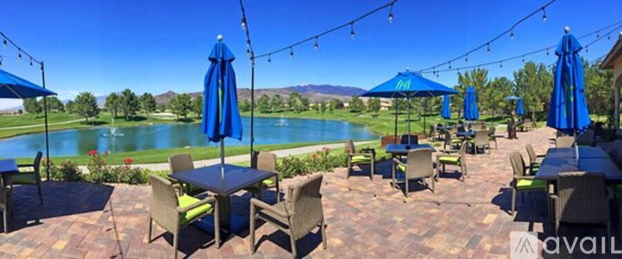 A patio with tables and chairs overlooking a lake.