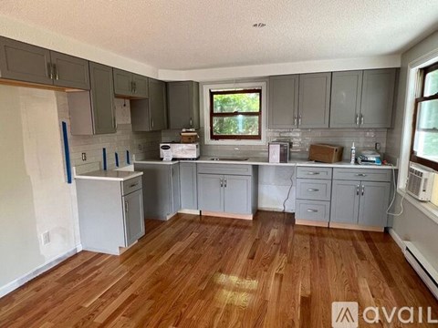 A kitchen with wooden floors and grey cabinets is available for rent.