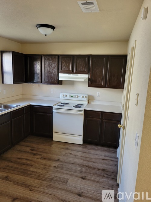 A kitchen with white appliances and dark wood cabinets.