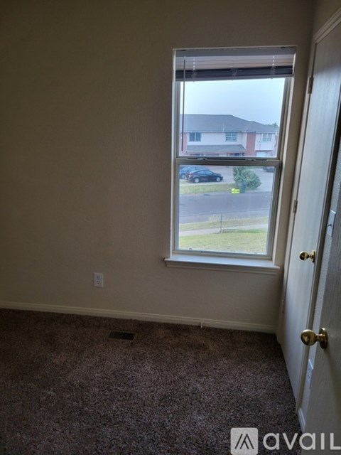A room with a carpeted floor and a window overlooking a street.