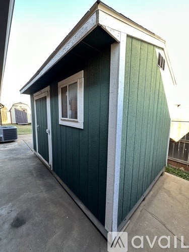 A green shed with a white trim and a window.