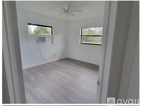 A room with a ceiling fan and two windows.