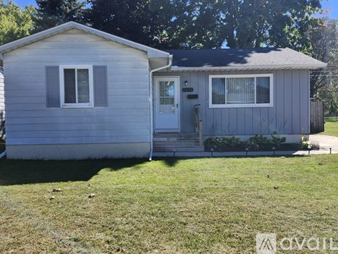 A small grey house with a white door and windows.