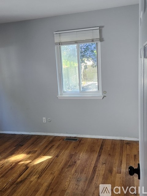 A room with a window and wooden flooring.