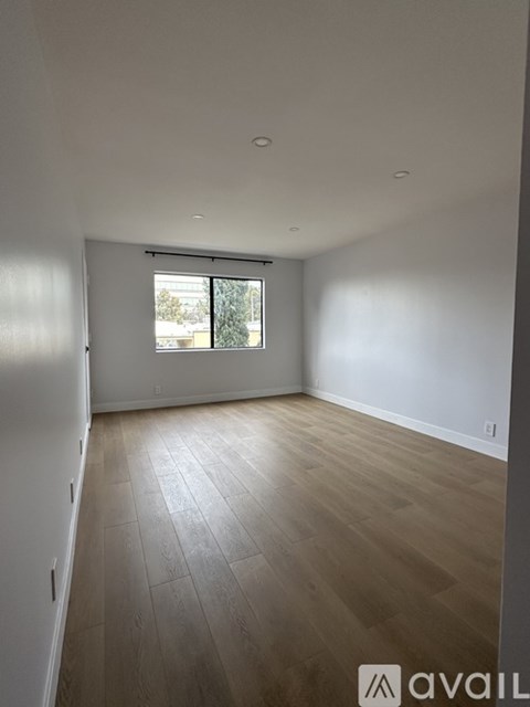 A spacious room with wooden flooring and a window.