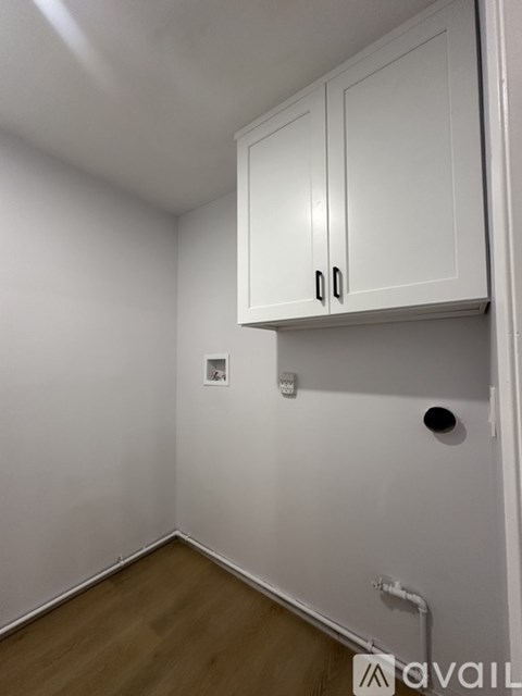 A white cabinet with two doors is mounted on a white wall.