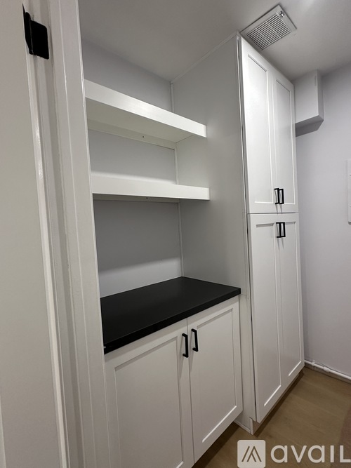 A kitchen with white cabinets and a black countertop.