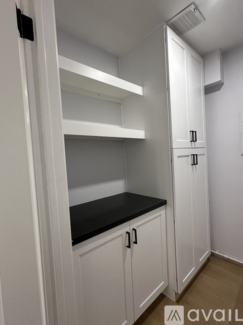 A kitchen with white cabinets and a black countertop.