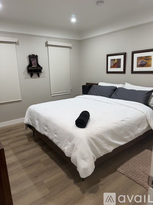 A bedroom with a white bed and a brown rug.