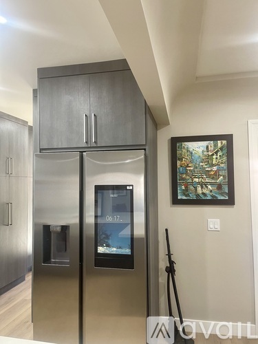 A modern kitchen with a refrigerator and a digital clock.