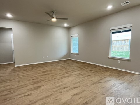 A spacious room with wooden flooring and a ceiling fan.