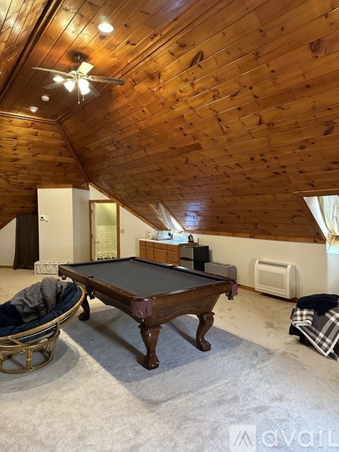 A pool table in a room with wooden walls and ceiling.