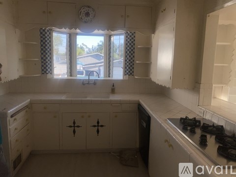 A kitchen with white cabinets and a window with a view of a house.