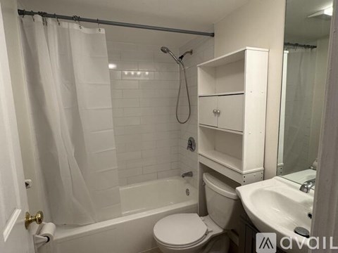 A white bathroom with a toilet, sink, and shower.