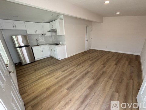 A kitchen with white cabinets and a wooden floor.