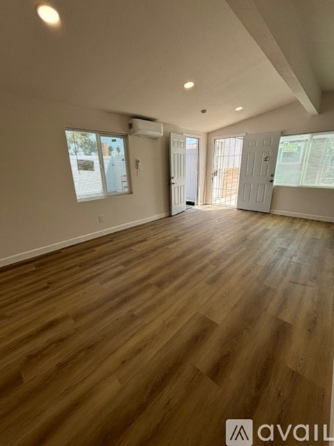 A spacious room with wooden flooring and a slanted ceiling.