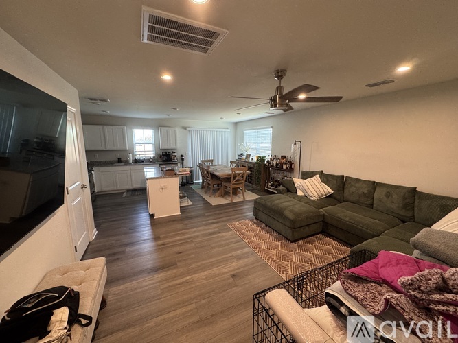A living room with a green couch and a fan on the ceiling.