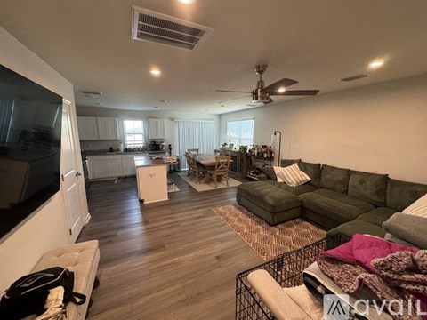 A living room with a green couch and a fan on the ceiling.