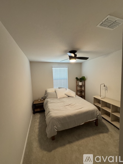 A bedroom with a bed, nightstand, and a fan.