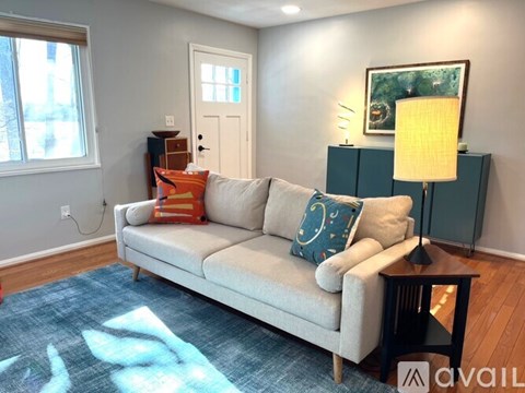 A living room with a couch, a lamp, and a painting on the wall.