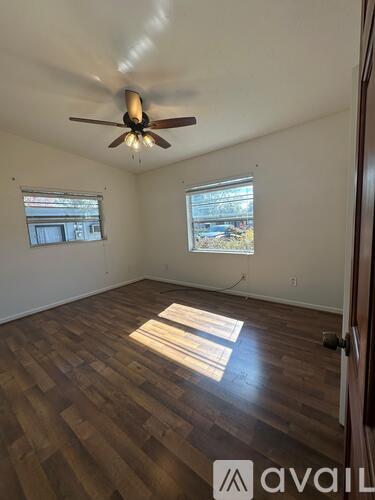 A room with a ceiling fan and wooden flooring.