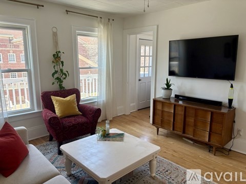 A living room with a red chair and a white table.