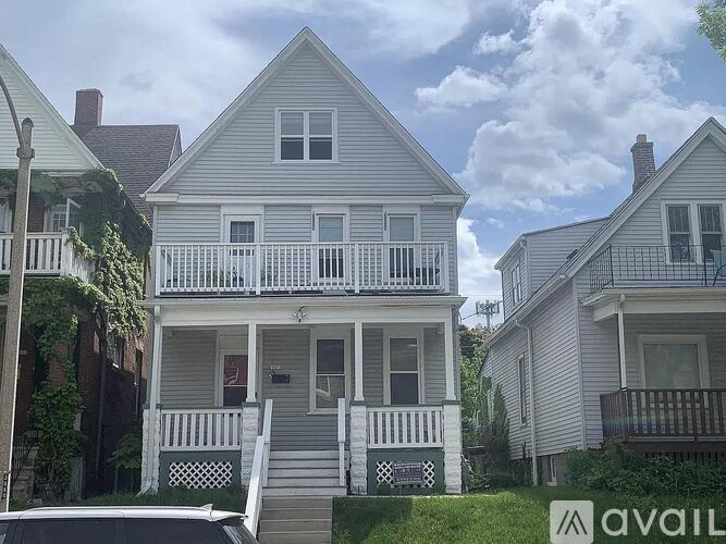 A two-story house with a porch and a sign that says "AVAIL".