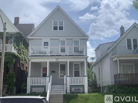 A two-story house with a porch and a sign that says "AVAIL".