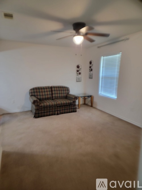 A room with a ceiling fan and a window with blinds.