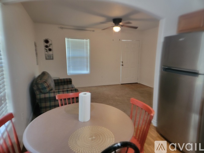 A kitchen with a table and chairs in the foreground and a refrigerator in the background.