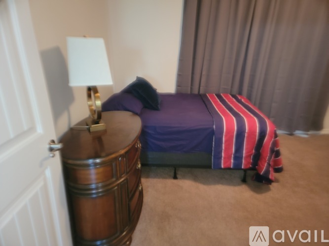 A bedroom with a bed, a nightstand, and a lamp.