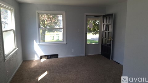 A room with a carpeted floor, a window, and a door.