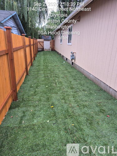 A lawn with a wooden fence and a house in the background.