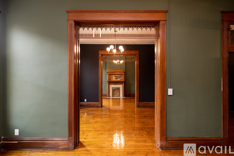 A room with a wooden floor and a large wooden doorway leading to another room.