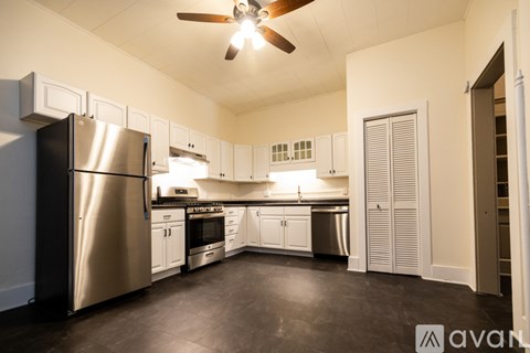A kitchen with a black refrigerator and white cabinets.