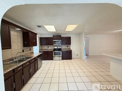 A kitchen with brown cabinets and a white tile floor.