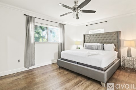 A bedroom with a large bed and a ceiling fan.