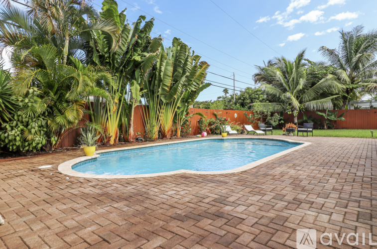 A pool surrounded by a brick patio and palm trees.
