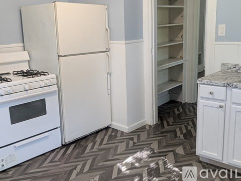 A kitchen with a white refrigerator, a white oven, and a patterned floor.