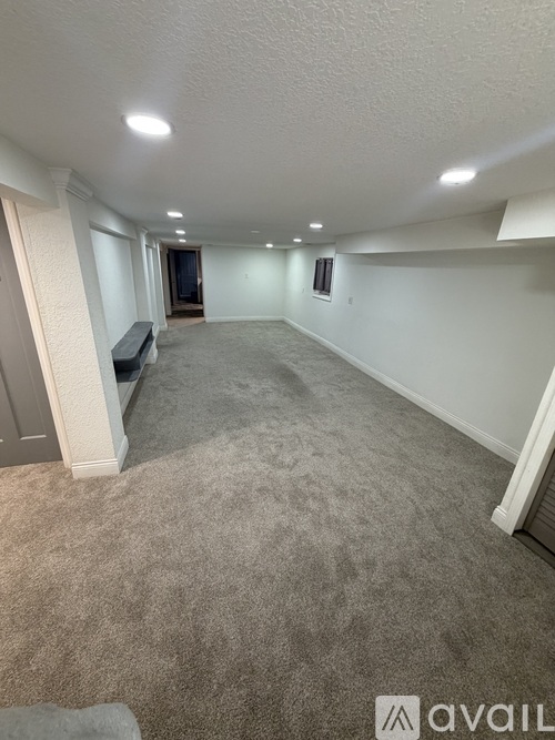A spacious room with carpeted floor and white walls.