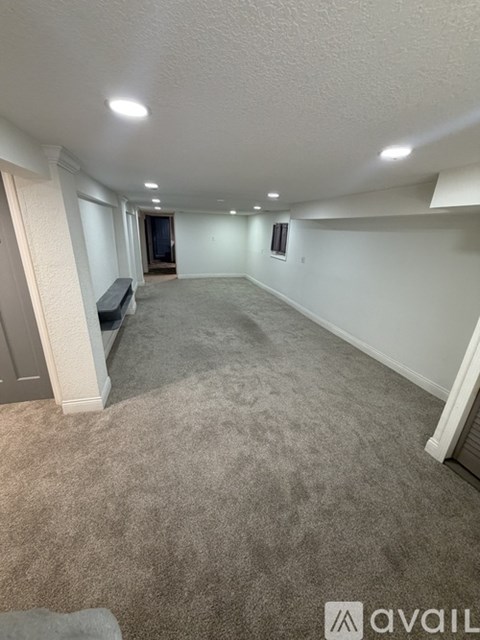 A spacious room with carpeted floor and white walls.