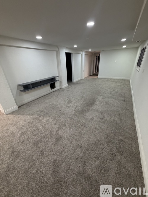 A spacious room with a grey carpet and white walls.