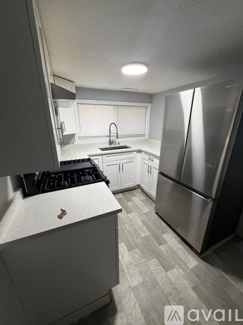 A kitchen with a stainless steel refrigerator and a black stove top.