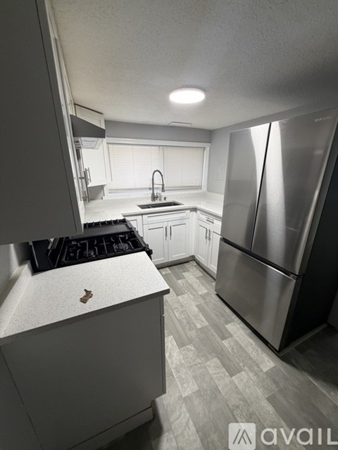 A kitchen with a stainless steel refrigerator and a black stove top.