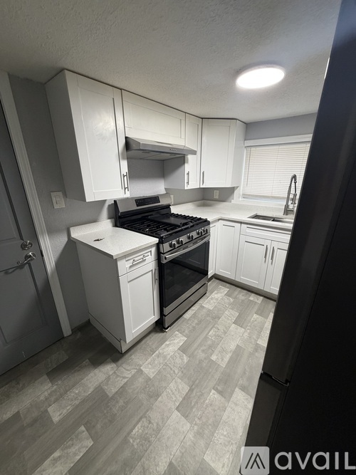 A kitchen with white cabinets and a black refrigerator.